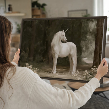A white unicorn standing in a shadowed forest clearing among dark tree trunks single framed canvas wall art held in hands