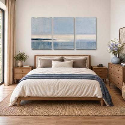 A minimal blue seascape with a pale horizon and soft vertical reflections 3 piece canvas wall art styled in an interior