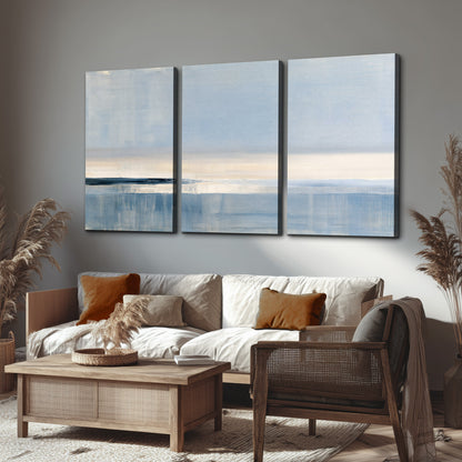 A minimal blue seascape with a pale horizon and soft vertical reflections 3 piece canvas wall art displayed in a rustic living room
