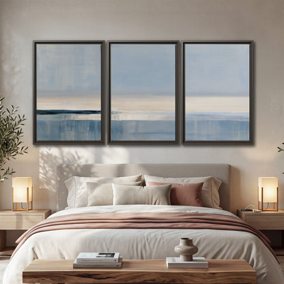 A minimal blue seascape with a pale horizon and soft vertical reflections 3 piece framed canvas wall art displayed in a bedroom