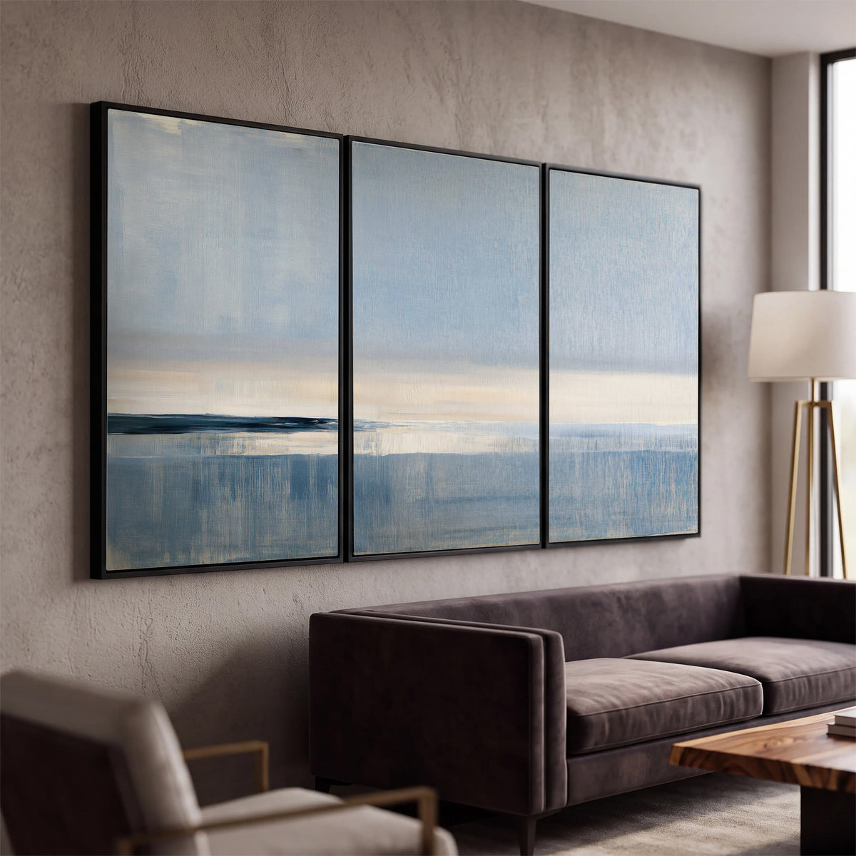 A minimal blue seascape with a pale horizon and soft vertical reflections 3 piece framed canvas wall art displayed in a modern living room