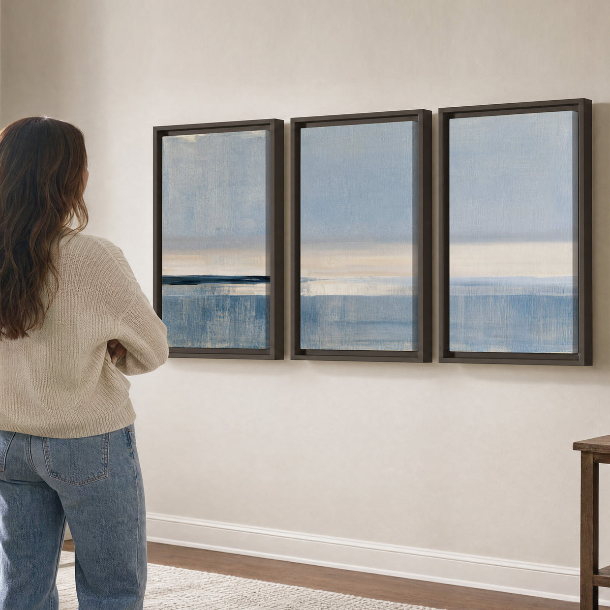 A minimal blue seascape with a pale horizon and soft vertical reflections 3 piece framed canvas wall art three panel arrangement on a wall