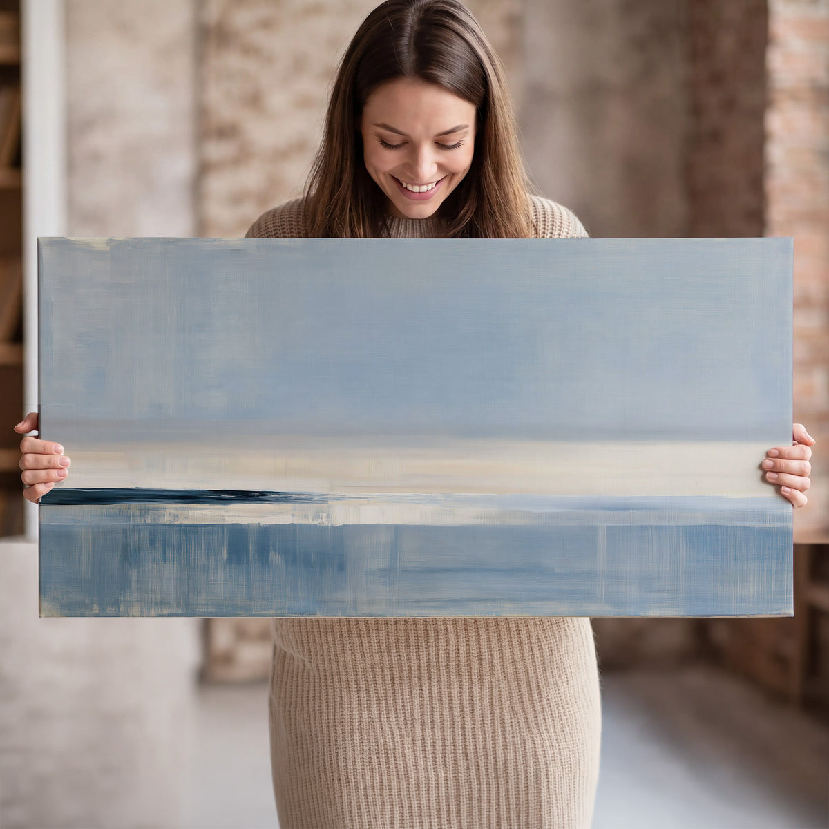 A minimal blue seascape with a pale horizon and soft vertical reflections single canvas wall art held in hands