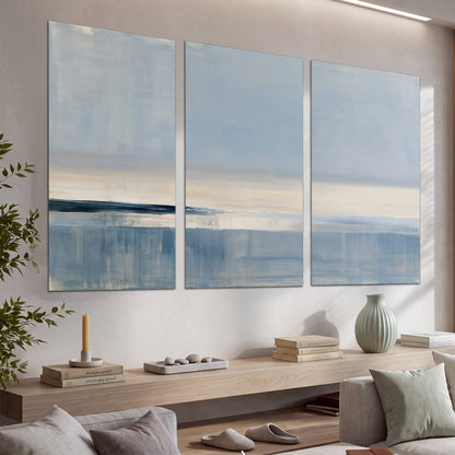 A minimal blue seascape with a pale horizon and soft vertical reflections set of 3 poster prints displayed in a console