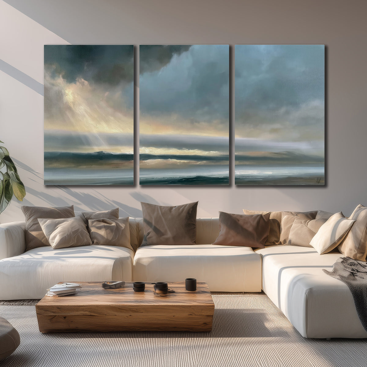 Dramatic blue-gray storm clouds breaking over a pale strip of ocean light 3 piece canvas wall art displayed in a living room
