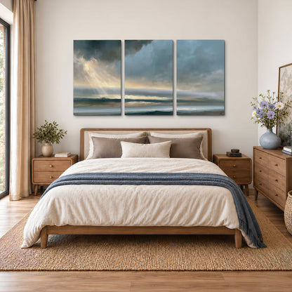 Dramatic blue-gray storm clouds breaking over a pale strip of ocean light 3 piece canvas wall art styled in an interior