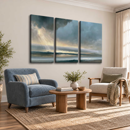 Dramatic blue-gray storm clouds breaking over a pale strip of ocean light 3 piece canvas wall art styled in an interior