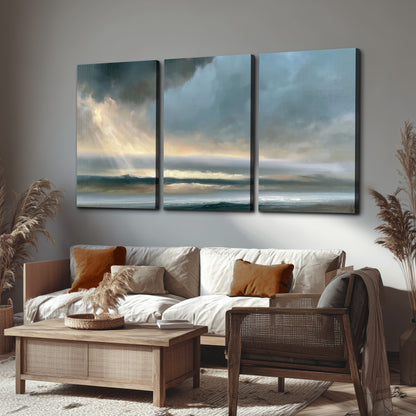 Dramatic blue-gray storm clouds breaking over a pale strip of ocean light 3 piece canvas wall art displayed in a rustic living room