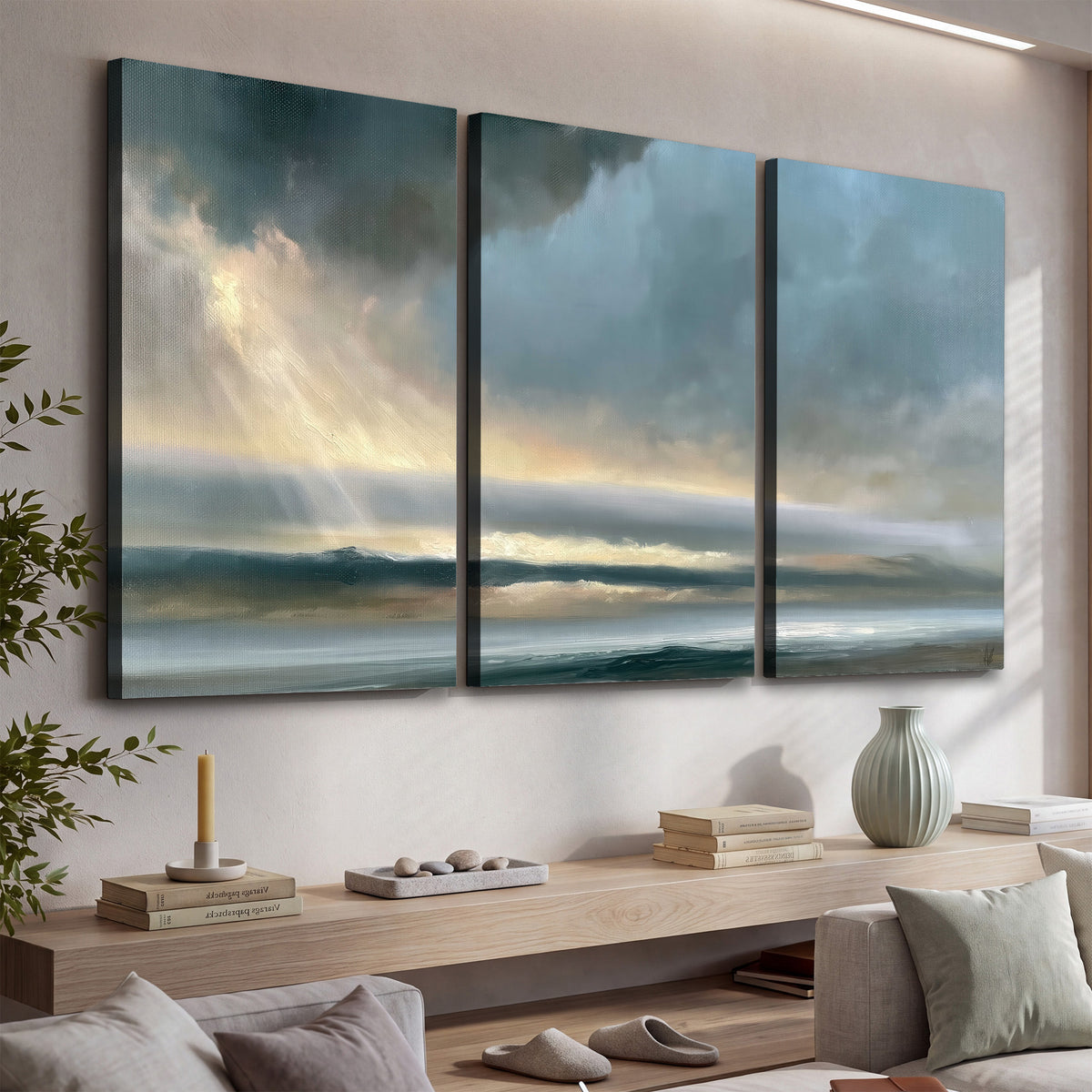 Dramatic blue-gray storm clouds breaking over a pale strip of ocean light 3 piece canvas wall art displayed in a console