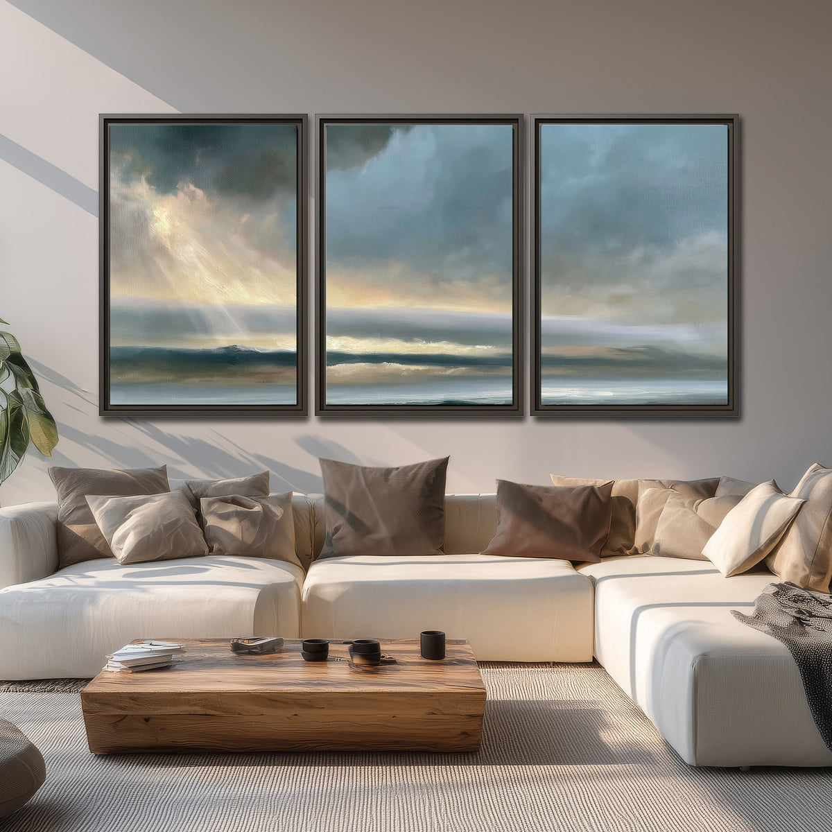 Dramatic blue-gray storm clouds breaking over a pale strip of ocean light 3 piece framed canvas wall art displayed in a living room