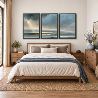 Dramatic blue-gray storm clouds breaking over a pale strip of ocean light 3 piece framed canvas wall art styled in an interior
