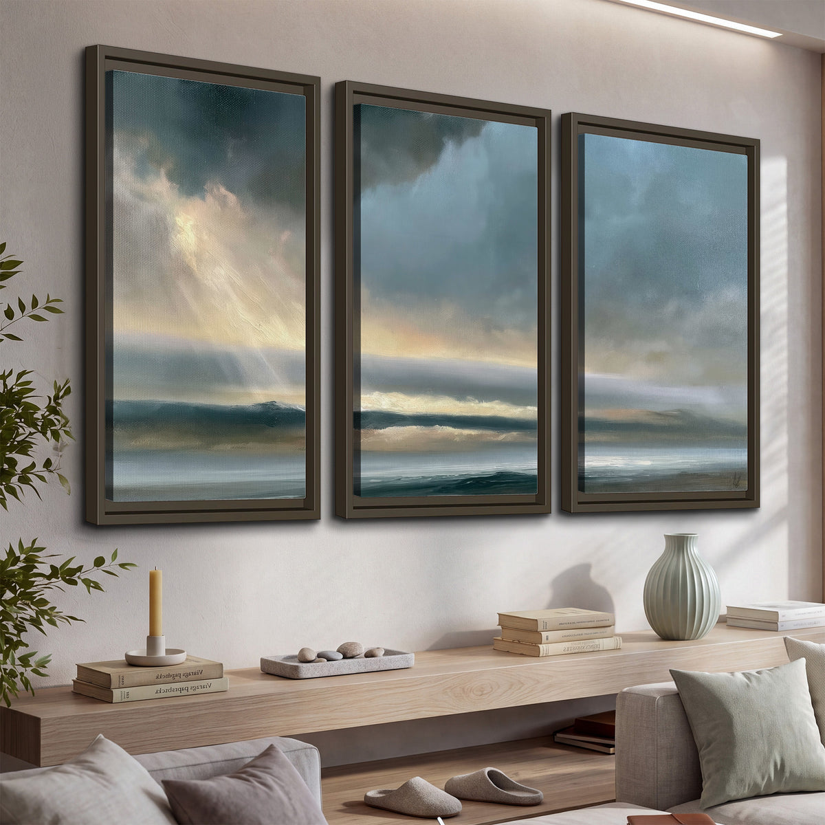 Dramatic blue-gray storm clouds breaking over a pale strip of ocean light 3 piece framed canvas wall art displayed in a console