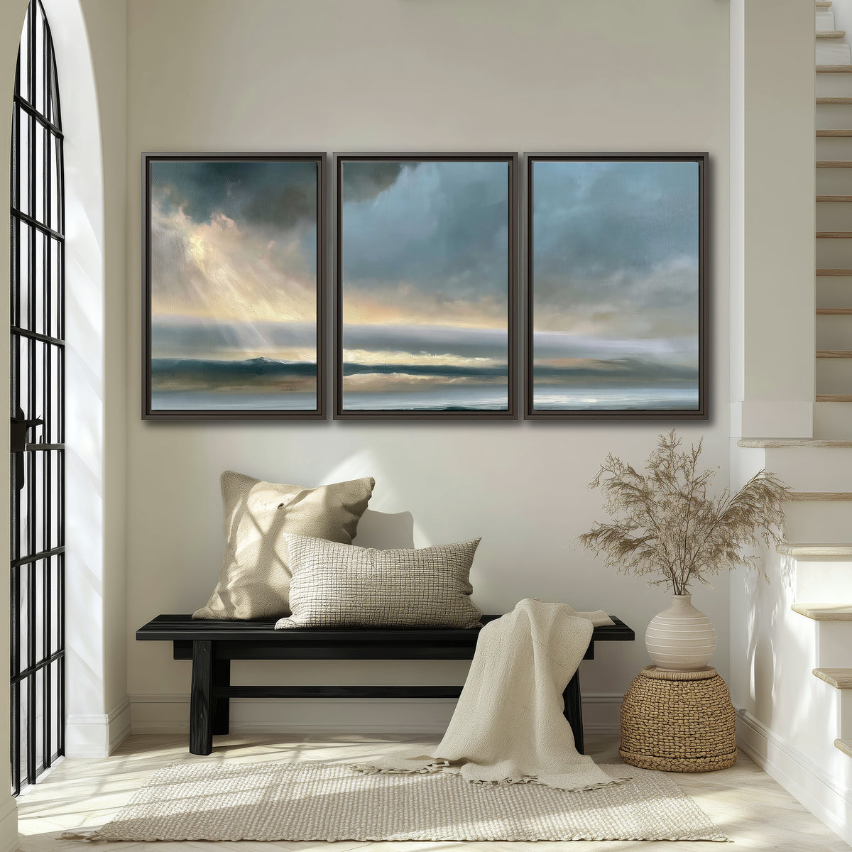 Dramatic blue-gray storm clouds breaking over a pale strip of ocean light 3 piece framed canvas wall art displayed in a entryway