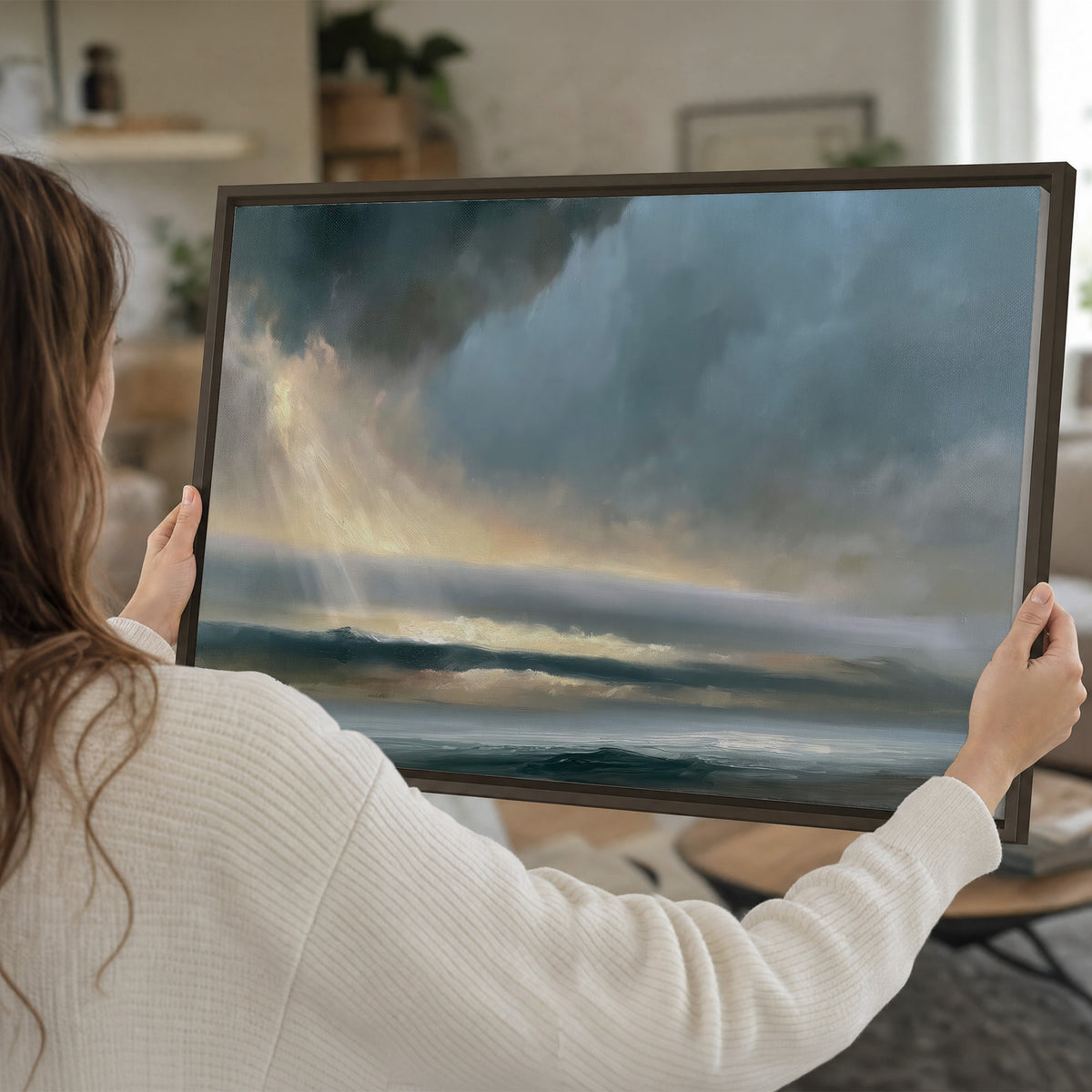 Dramatic blue-gray storm clouds breaking over a pale strip of ocean light single framed canvas wall art held in hands