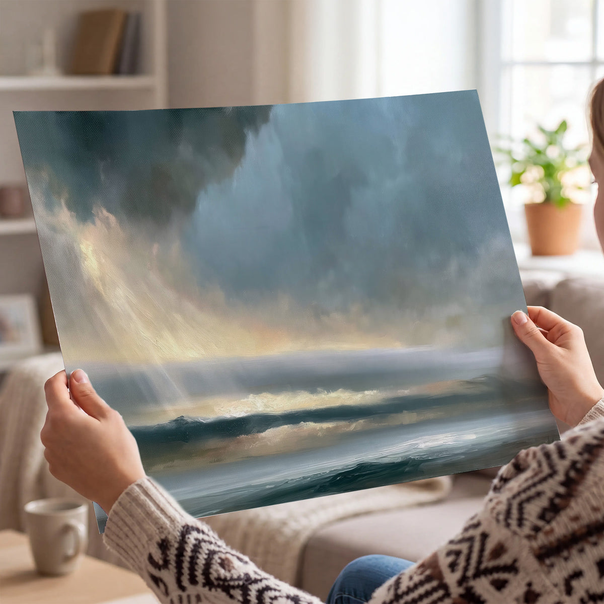 Dramatic blue-gray storm clouds breaking over a pale strip of ocean light single poster print held in hands