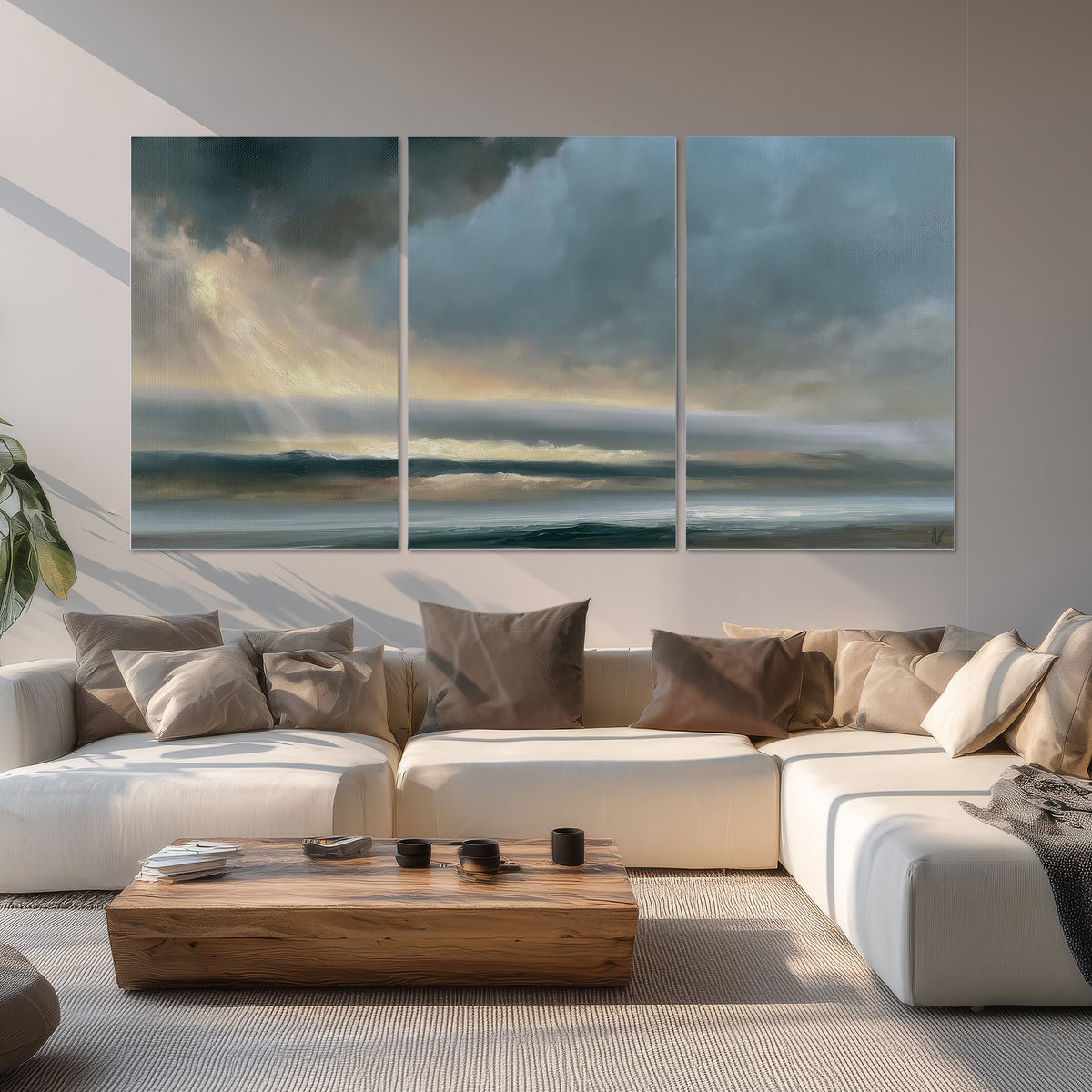 Dramatic blue-gray storm clouds breaking over a pale strip of ocean light set of 3 poster prints displayed in a living room