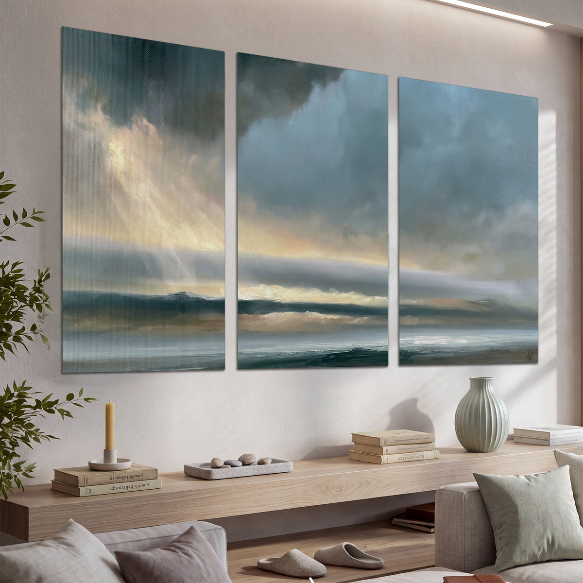 Dramatic blue-gray storm clouds breaking over a pale strip of ocean light set of 3 poster prints displayed in a console