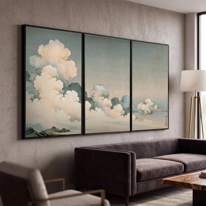 Soft cream clouds gathered low in a muted blue-green sky 3 piece framed canvas wall art displayed in a modern living room