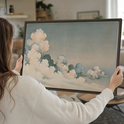 Soft cream clouds gathered low in a muted blue-green sky single framed canvas wall art held in hands