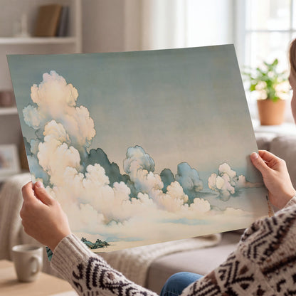 Soft cream clouds gathered low in a muted blue-green sky single poster print held in hands