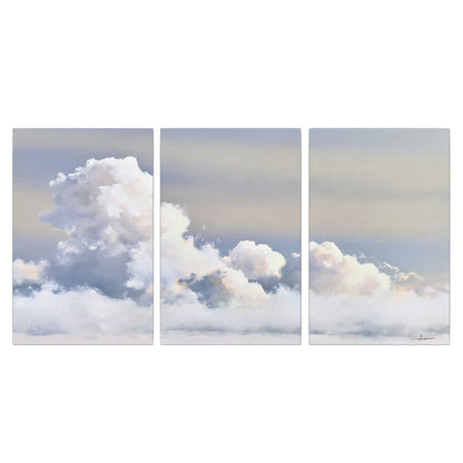Large white clouds rising through a pale blue sky with gentle warm highlights 3 piece canvas wall art viewed straight on