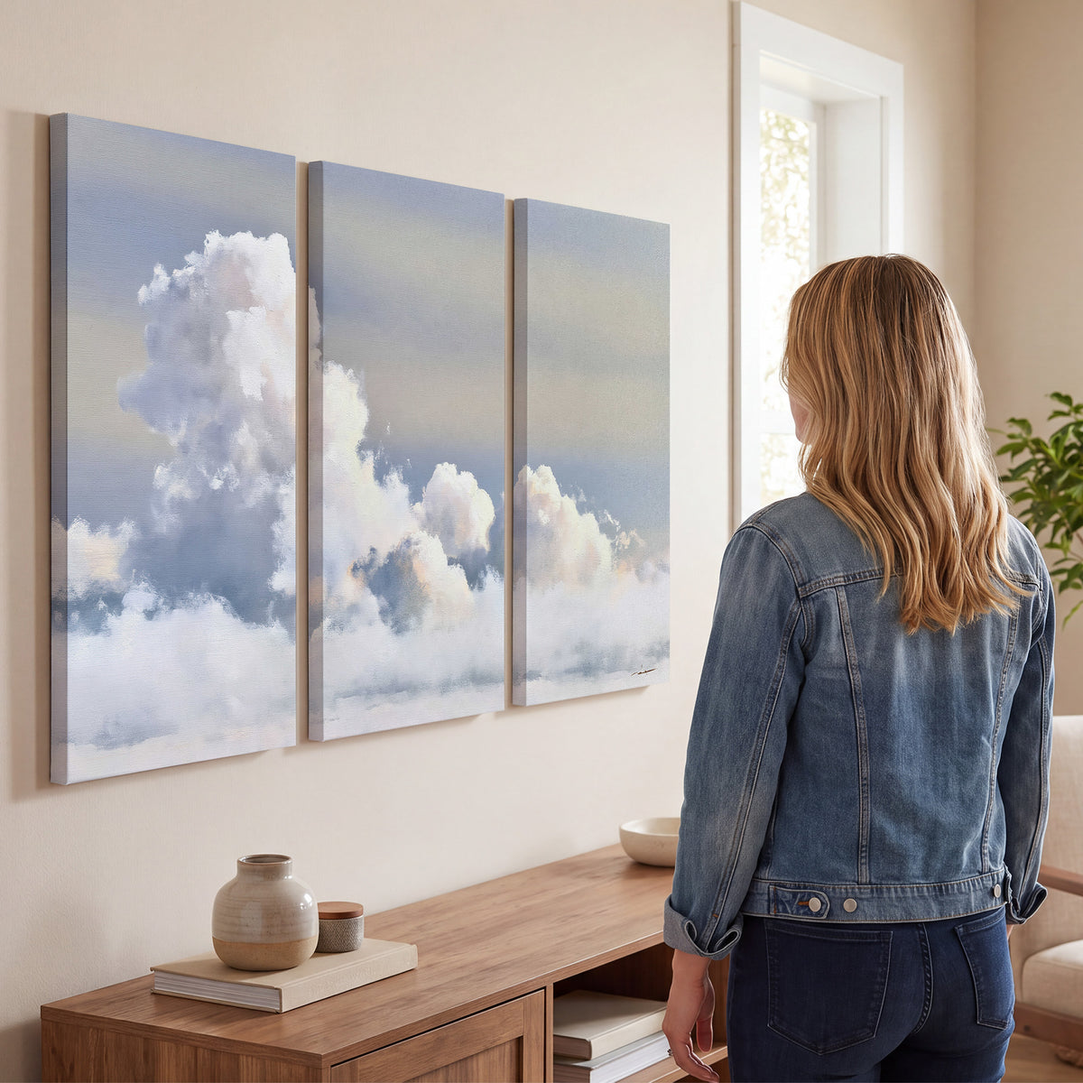 Large white clouds rising through a pale blue sky with gentle warm highlights 3 piece canvas wall art three panel arrangement on a wall