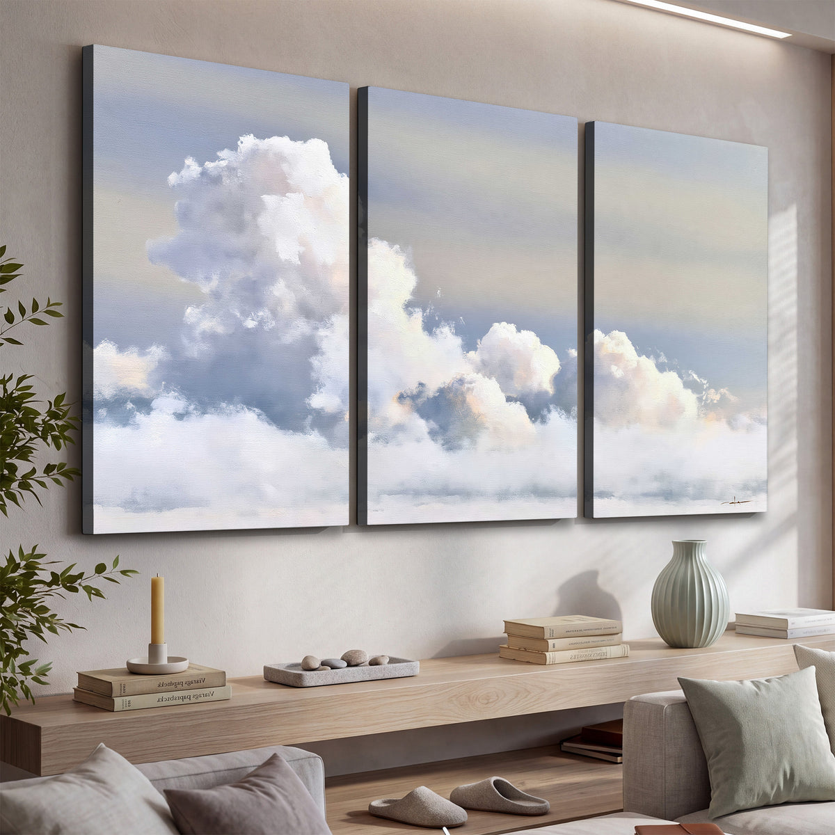 Large white clouds rising through a pale blue sky with gentle warm highlights 3 piece canvas wall art displayed in a console