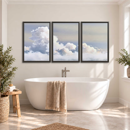 Large white clouds rising through a pale blue sky with gentle warm highlights 3 piece framed canvas wall art styled in an interior