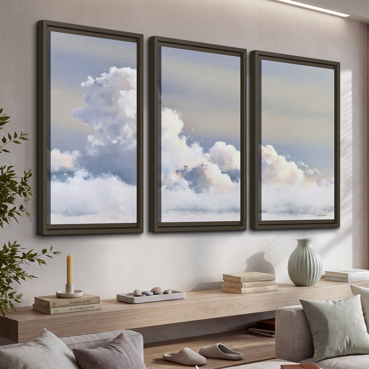 Large white clouds rising through a pale blue sky with gentle warm highlights 3 piece framed canvas wall art displayed in a console