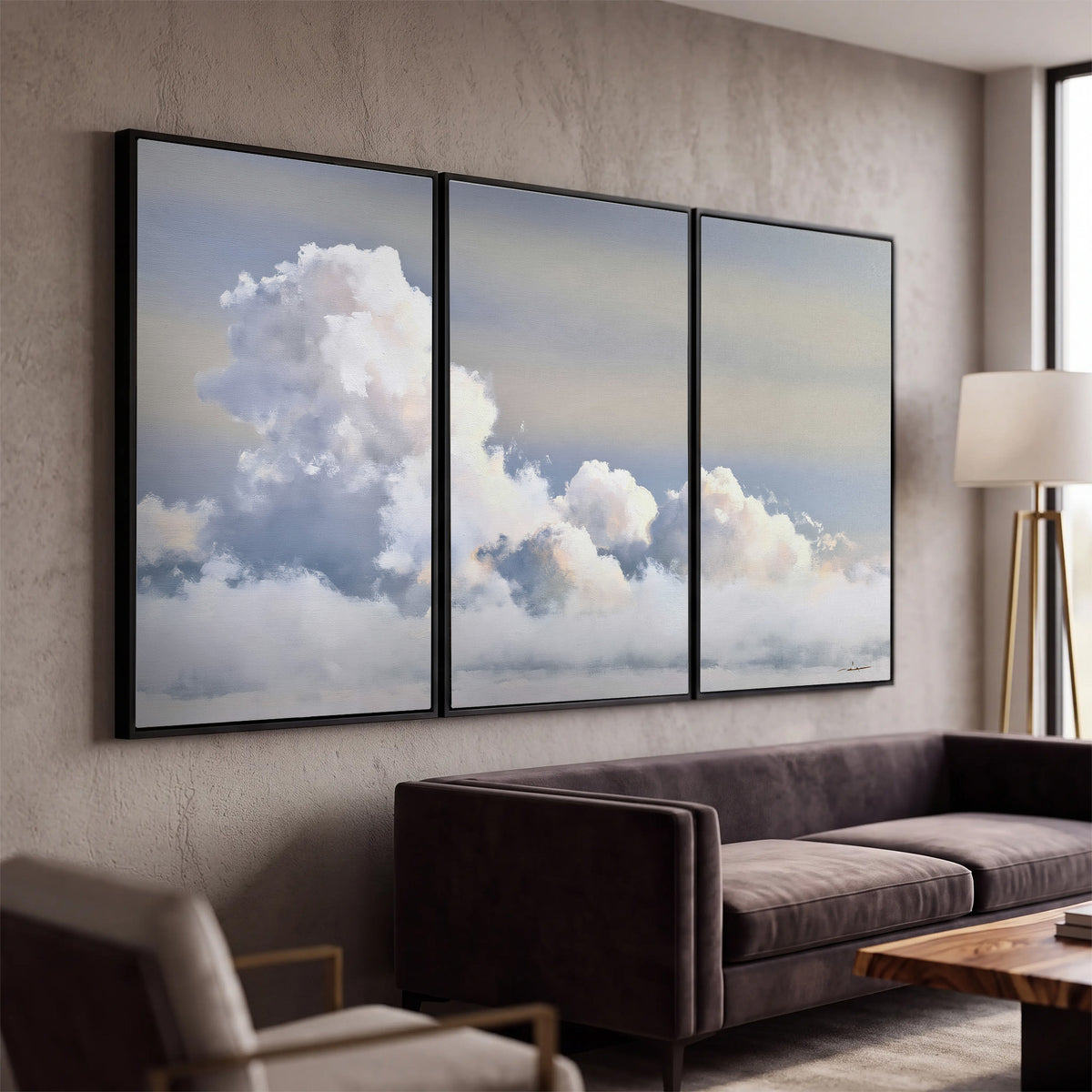 Large white clouds rising through a pale blue sky with gentle warm highlights 3 piece framed canvas wall art displayed in a modern living room