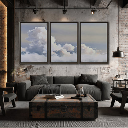 Large white clouds rising through a pale blue sky with gentle warm highlights 3 piece framed canvas wall art displayed in a industrial room