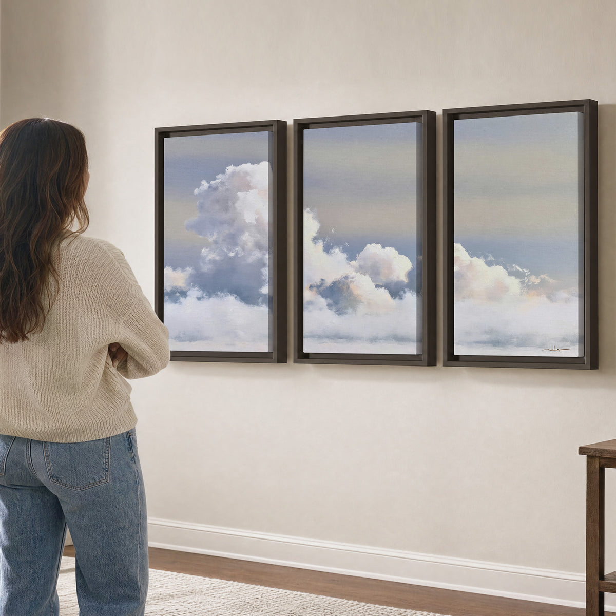 Large white clouds rising through a pale blue sky with gentle warm highlights 3 piece framed canvas wall art three panel arrangement on a wall