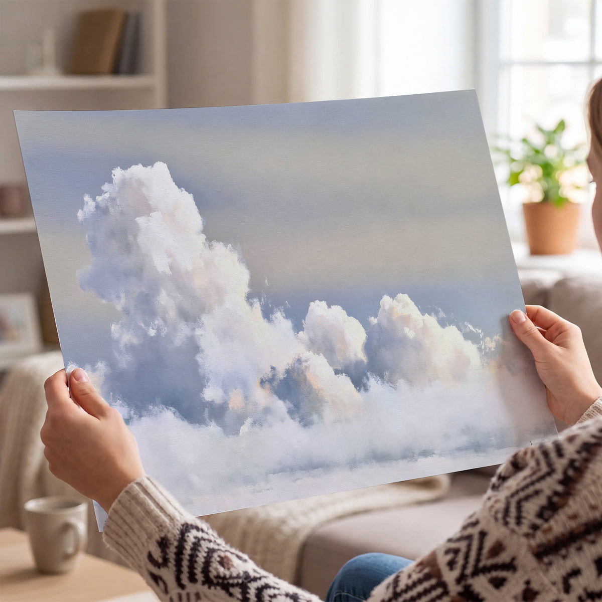 Large white clouds rising through a pale blue sky with gentle warm highlights single poster print held in hands