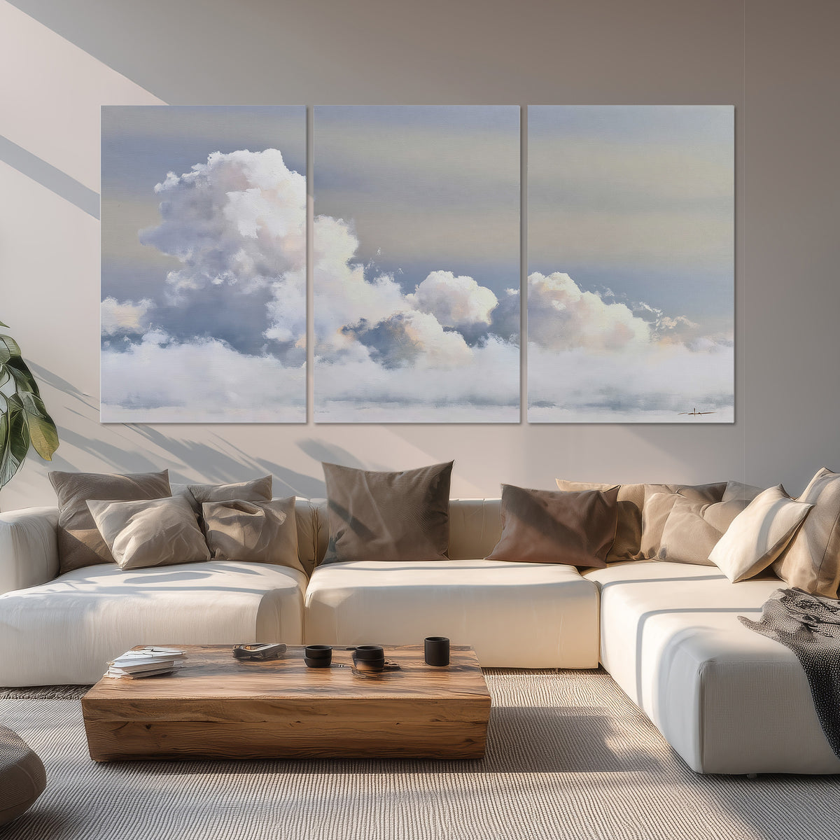 Large white clouds rising through a pale blue sky with gentle warm highlights set of 3 poster prints displayed in a living room