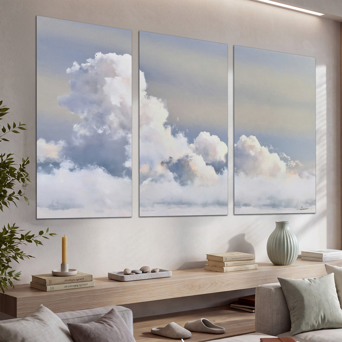Large white clouds rising through a pale blue sky with gentle warm highlights set of 3 poster prints displayed in a console