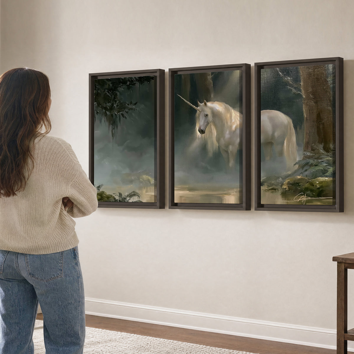 A white unicorn standing near rocks and a quiet stream in a green woodland 3 piece framed canvas wall art three panel arrangement on a wall