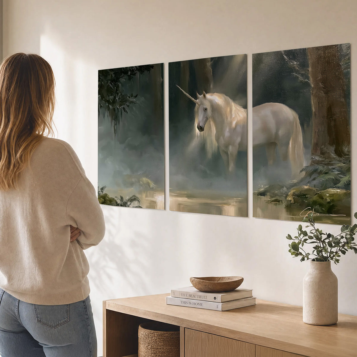 A white unicorn standing near rocks and a quiet stream in a green woodland set of 3 poster prints three panel arrangement on a wall
