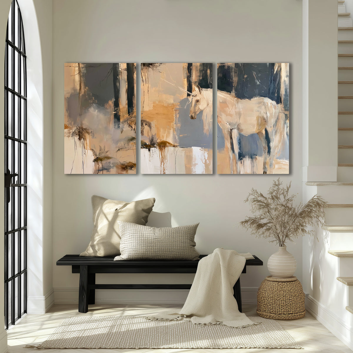 A pale unicorn emerging from loose vertical strokes of blue, ochre and cream 3 piece canvas wall art displayed in a entryway