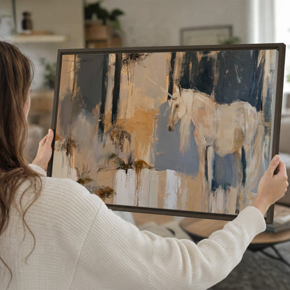 A pale unicorn emerging from loose vertical strokes of blue, ochre and cream single framed canvas wall art held in hands