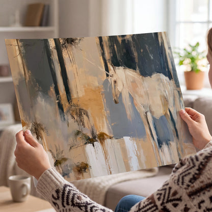 A pale unicorn emerging from loose vertical strokes of blue, ochre and cream single poster print held in hands