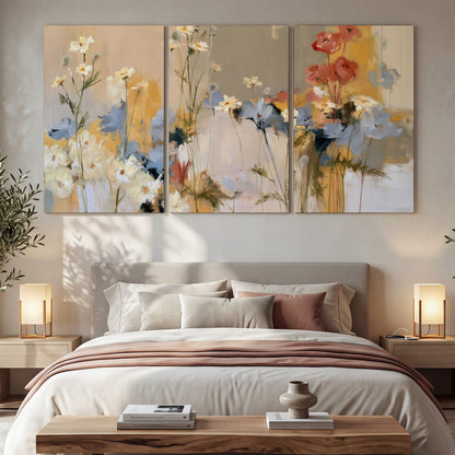 Loose white and yellow flowers set against vertical blue and golden strokes 3 piece canvas wall art displayed in a bedroom