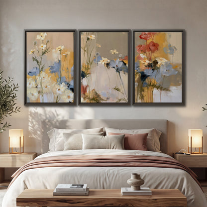Loose white and yellow flowers set against vertical blue and golden strokes 3 piece framed canvas wall art displayed in a bedroom