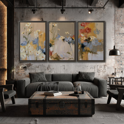 Loose white and yellow flowers set against vertical blue and golden strokes 3 piece framed canvas wall art displayed in a industrial room