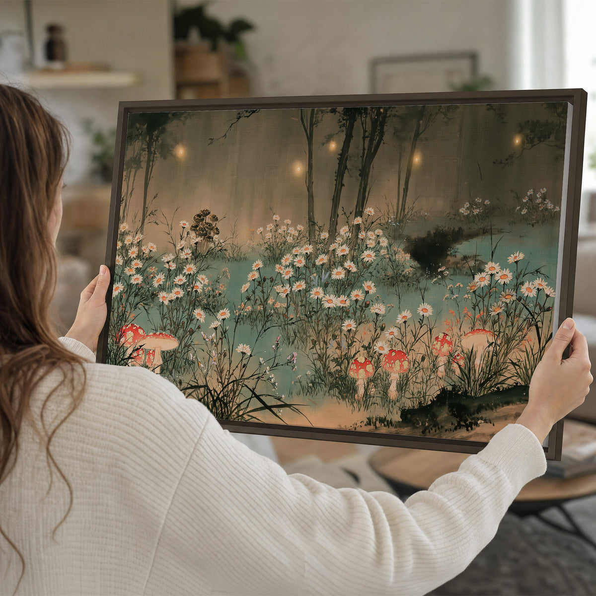 A wide meadow of white daisies and small red mushrooms beneath dark woodland trees single framed canvas wall art held in hands