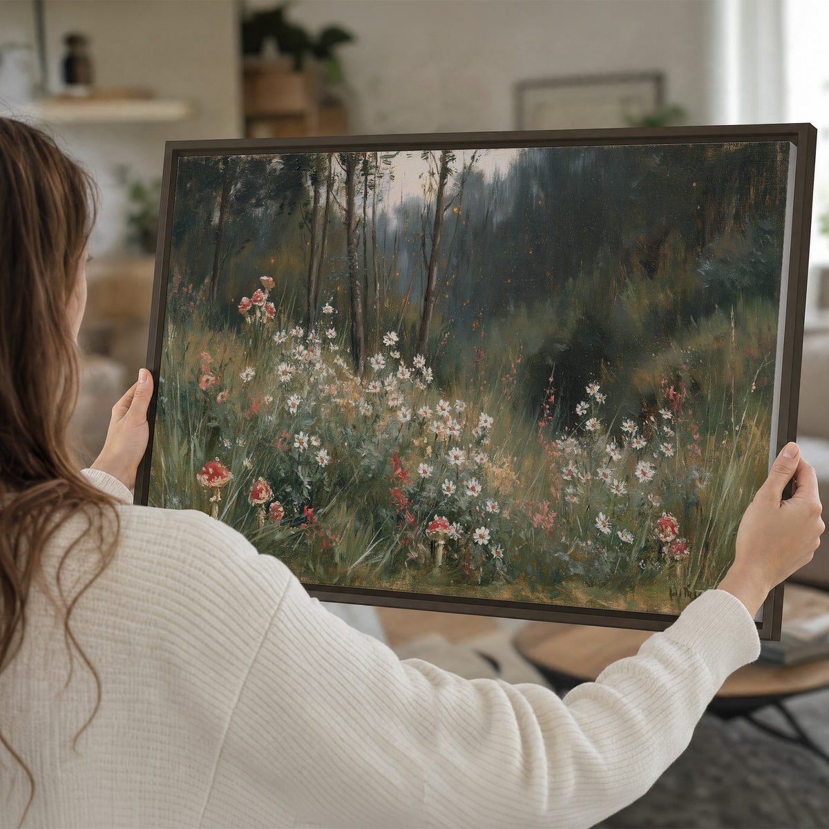 A soft woodland meadow filled with pale flowers and scattered warm red accents single framed canvas wall art held in hands
