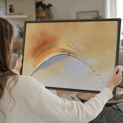 A sweeping ochre and orange arc with fine blue accents on a warm cream background single framed canvas wall art held in hands