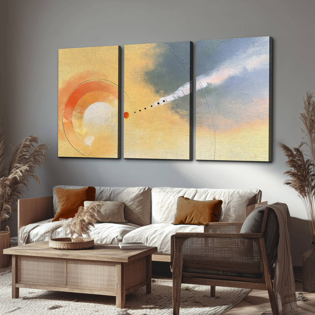 A warm orange circular form and diagonal pale streaks across a muted yellow and blue field 3 piece canvas wall art displayed in a rustic living room