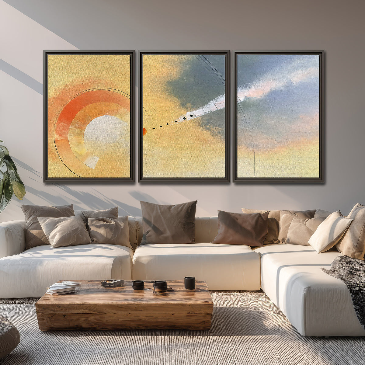 A warm orange circular form and diagonal pale streaks across a muted yellow and blue field 3 piece framed canvas wall art displayed in a living room