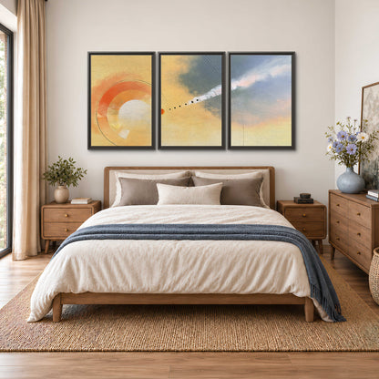 A warm orange circular form and diagonal pale streaks across a muted yellow and blue field 3 piece framed canvas wall art styled in an interior