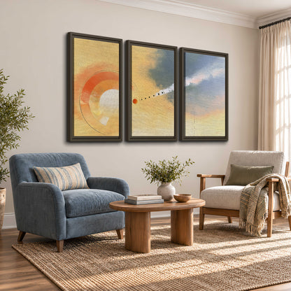 A warm orange circular form and diagonal pale streaks across a muted yellow and blue field 3 piece framed canvas wall art styled in an interior